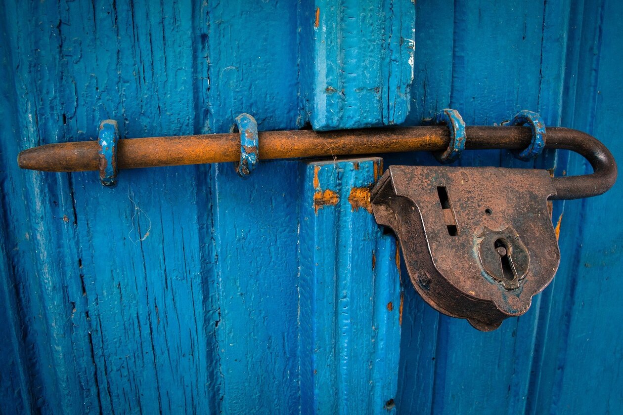 Eine hölzerne Tür wird von einem Eisenschloss verschlossen